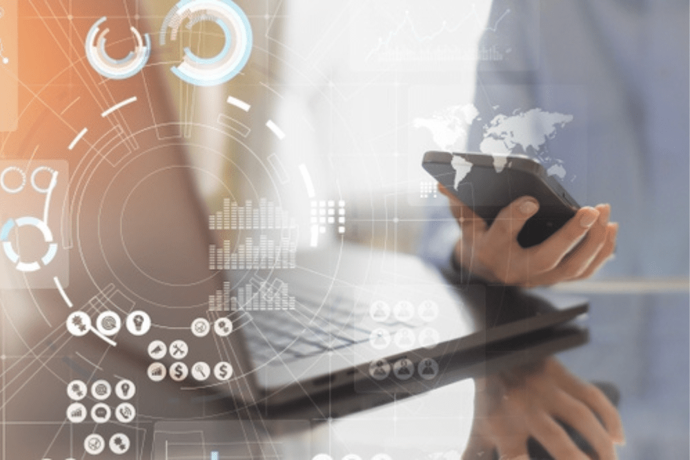 Person using phone and laptop with digital data interface overlay.
